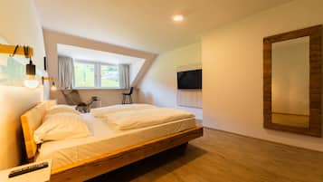A modern bedroom with a wooden bed, a TV mounted on the wall, and a large mirror.