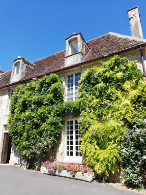 A historic building with a traditional tiled roof, a central window with white shutters, and lush greenery climbing the walls. - Large manor house for rent in Normandy, a stone's throw from Suisse Normande! (fresné-la-mère)
