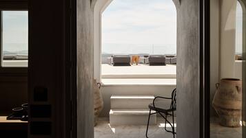 A narrow passageway leading to a terrace with a view of the sea.