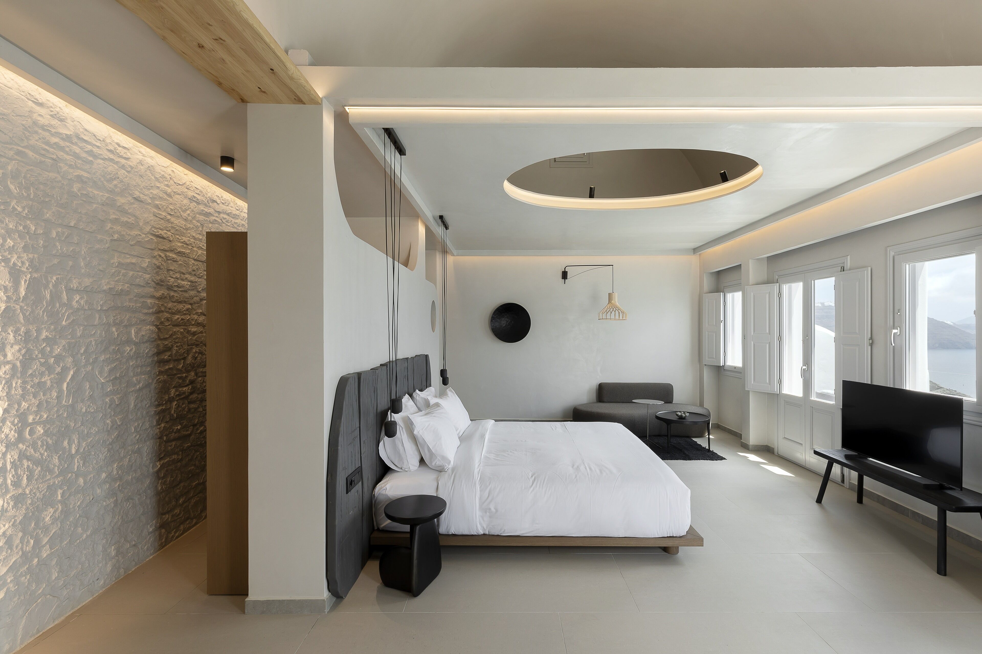 Un dormitorio moderno con una cama grande, un televisor y vistas al exterior.