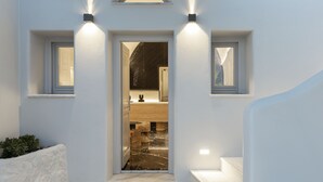 A modern entrance with a white exterior, a door leading to a bathroom, and two wall-mounted lights.