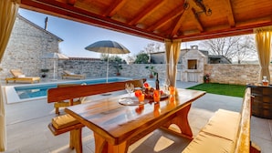A wooden outdoor dining area with a pool, stone walls, and a stone building in the background. - Romantic Istrian Villa Nima with private pool (Glavani)