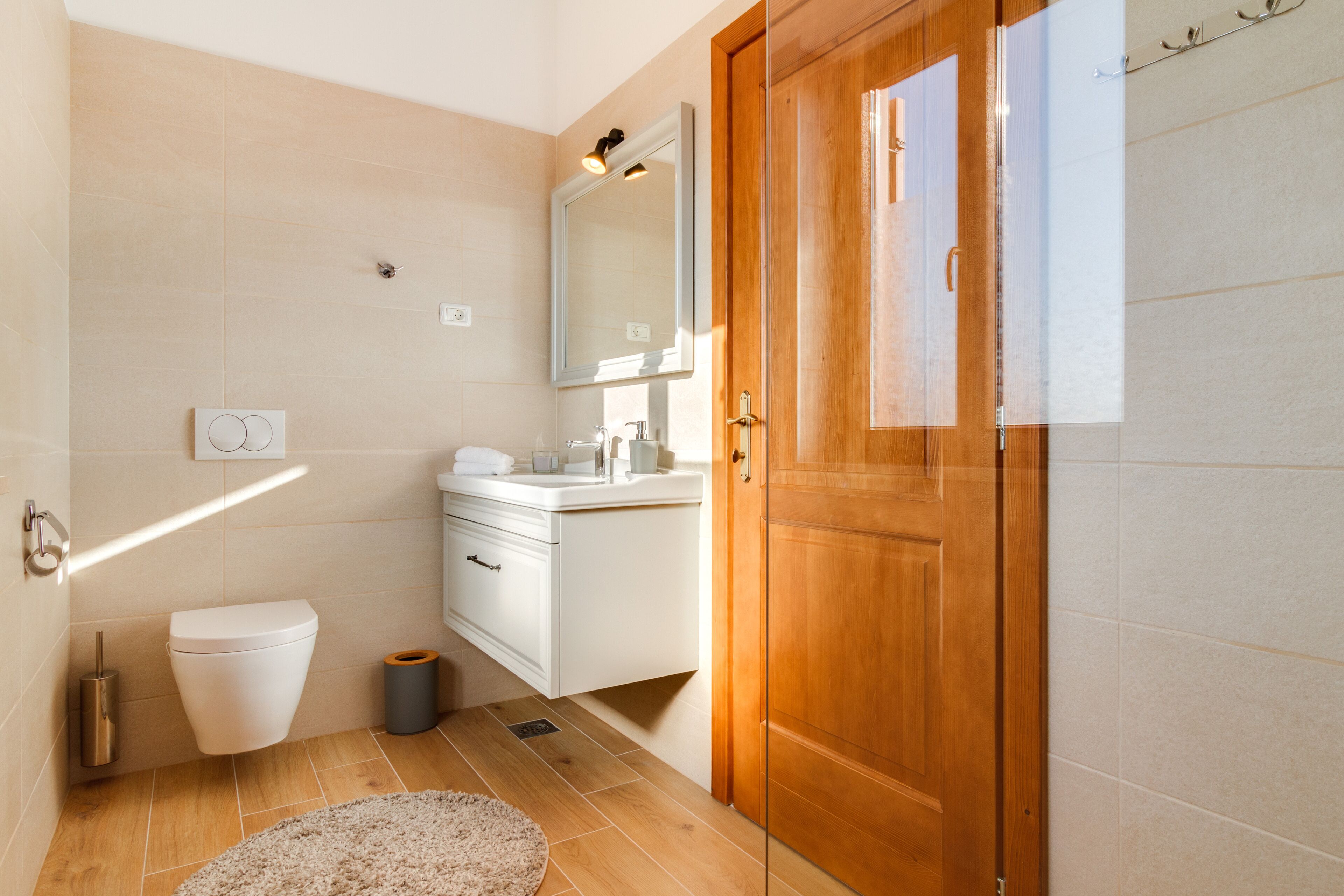A bathroom with a toilet, sink, mirror, and wooden door.