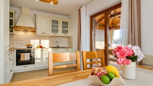 A modern kitchen with white cabinets, a wooden dining table, and a fruit bowl. - Romantic Istrian Villa Nima with private pool (Glavani)