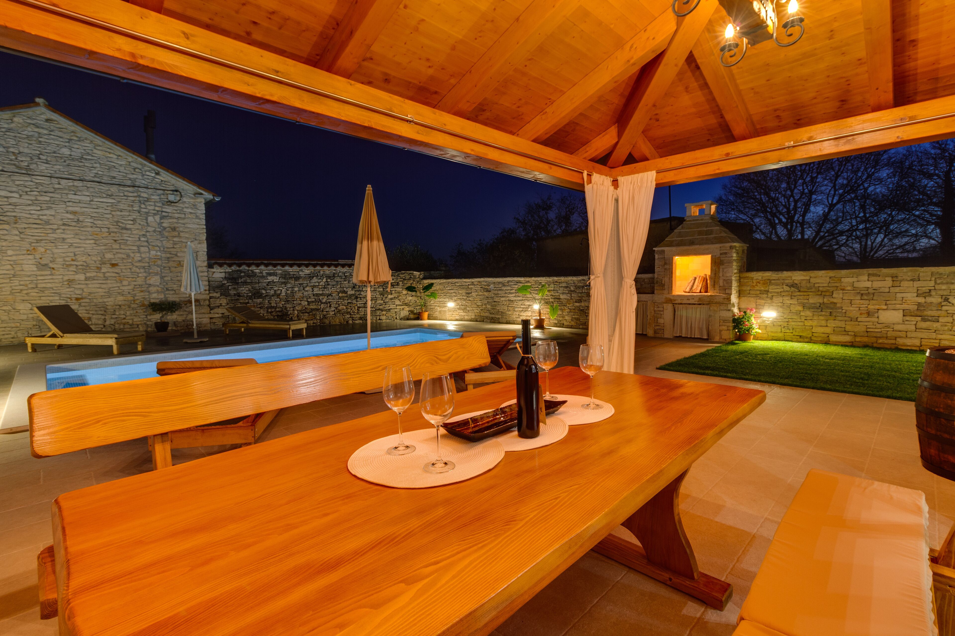 Un área de comedor al aire libre con madera, una pared de piedra y un edificio de piedra al fondo.
