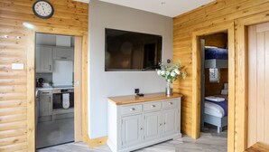 A modern log cabin interior with a kitchen, a dining area, and a sleeping loft. - Hilltop Lodge (Corwen)