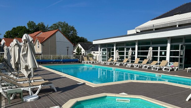 A swimming pool with lounge chairs and umbrellas, surrounded by buildings. - House (2Ch) with covered swimming pool Pornichet La Baule (Pornichet)