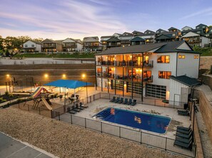 Un edificio de varios pisos con piscina, mobiliario exterior y un parque infantil.
