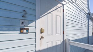 A white door with a mailbox and a sign on the house's exterior wall. - Cloud Suite on Duval Street with Balcony (Key West)