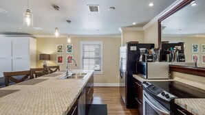 A kitchen with a large island, built-in appliances, and a dining area with chairs. - Cloud Suite on Duval Street with Balcony (Key West)