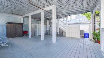 Un patio techado al aire libre con cubierta de madera, barandillas blancas y cerca blanca.