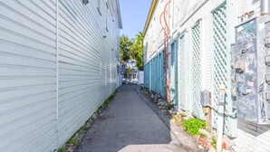 A narrow alleyway flanked by white buildings with metal fences and graffiti. - Cloud Suite on Duval Street with Balcony (Key West)
