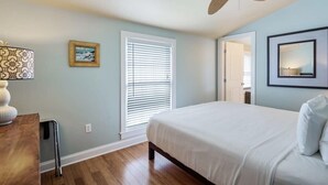 A bedroom with a bed, a ceiling fan, a window with blinds, a bedside table, and a framed picture on the wall. - Cloud Suite on Duval Street with Balcony (Key West)