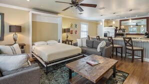 A hotel room with a bed, a sofa, a coffee table, a ceiling fan, and a kitchen area. - Cloud Suite on Duval Street with Balcony (Key West)