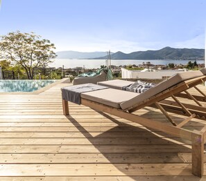 Une terrasse en bois avec des chaises longues et une piscine.