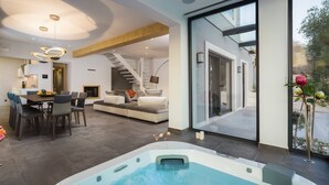 A modern interior with a dining area, a sofa, a hot tub, and a staircase leading to an outdoor area. - Luxury Seafront Villa Blue Heaven Ciovo with Pool (Okrug Gornji)