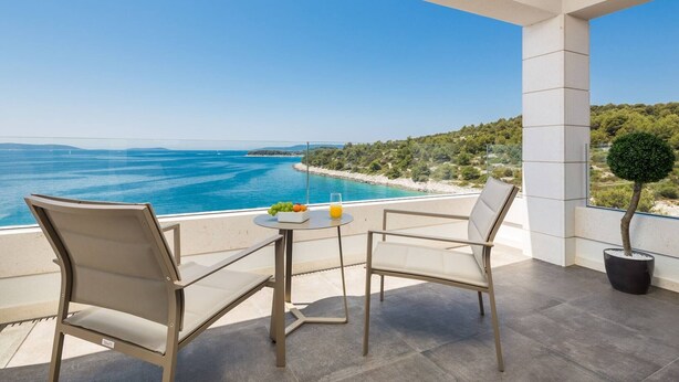 A balcony with a table and two chairs overlooking a coastal view. - Luxury Seafront Villa Blue Heaven Ciovo with Pool (Okrug Gornji)