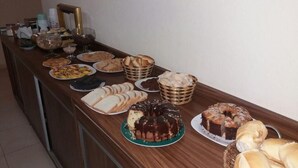 Une table de buffet proposant une variété d’aliments, notamment des gâteaux, des pâtisseries et du pain.