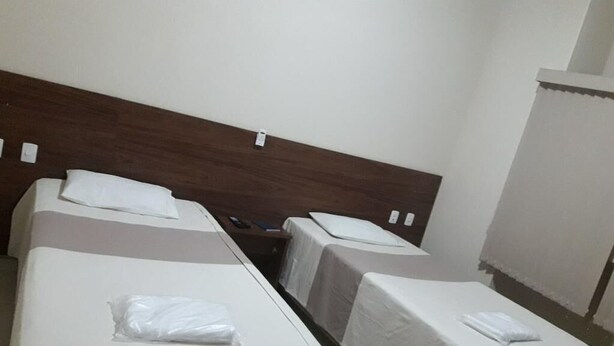 Une chambre d’hôtel avec deux lits simples, chacun recouvert d’une courtepointe blanche et doté d’un oreiller.