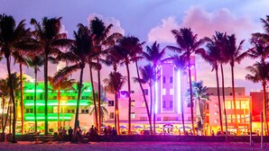 A brightly lit hotel with multiple floors, palm trees, and outdoor seating areas. - Oceanview Private Condo at The Setai -190102 (Miami Beach)