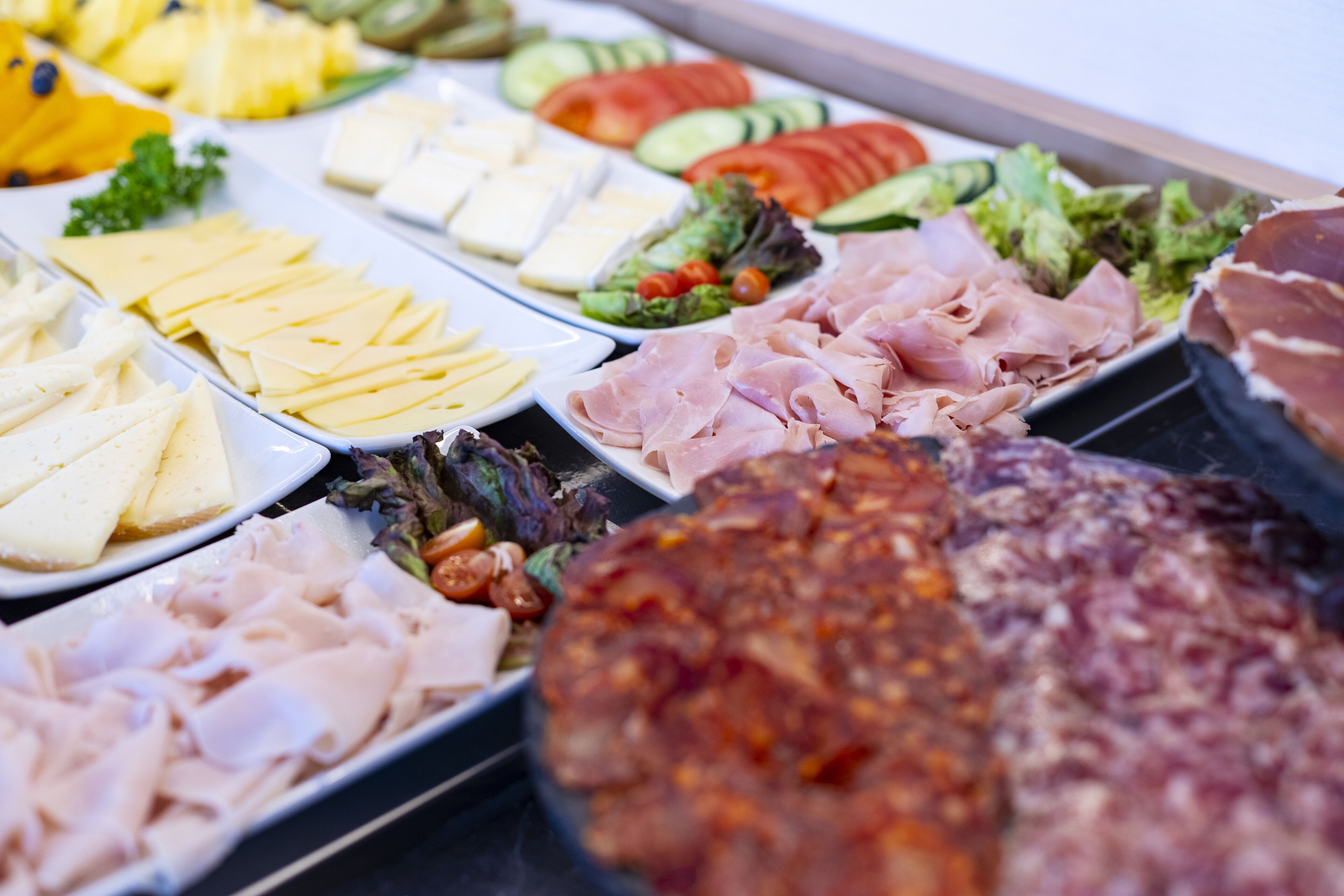 Een buffet met verschillende soorten eten, zoals vlees, kaas en groenten.