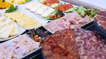 Een buffet met verschillende soorten eten, zoals vlees, kaas en groenten.