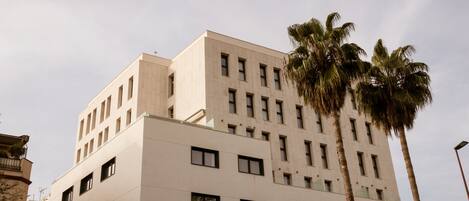 A multi-story building with a modern architectural design, featuring a symmetrical facade and numerous windows.