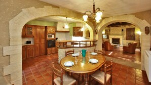 A spacious kitchen with a central island, wooden cabinets, and a dining area with a round table and chairs.