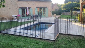 A house with a swimming pool, a patio with outdoor furniture, and a fenced yard.