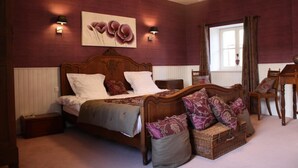 Een slaapkamer met een houten bed, een nachtkastje, een rieten mand en een kroonluchter.