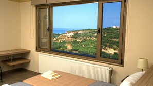 Une chambre dotée d’une grande fenêtre donnant sur un paysage côtier.