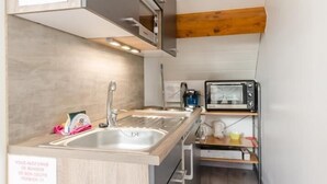 A compact kitchen with a sink, a microwave, and a toaster. There are signs on the wall, one indicating a no-smoking area and another about a cleaning service. - Le Gite du Pigeonnier (VILLENAUXE LA GRANDE)