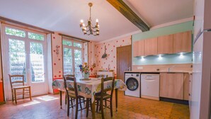 A dining area with a table and chairs, a washing machine, and a kitchen with wooden cabinets.
