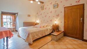 A bedroom with a bed, bedside tables, a wooden bench, a door, and a window with curtains.