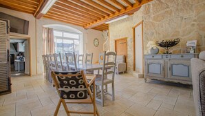 Une salle à manger spacieuse avec un haut plafond en bois, des murs en pierre et une vue sur l’extérieur.