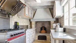 Une cuisine moderne dotée d’une cuisinière intégrée, de meubles blancs et d’une cheminée en pierre.