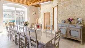 Un espace repas comprenant une grande table et des chaises, un mur en pierre et un plafond en bois.