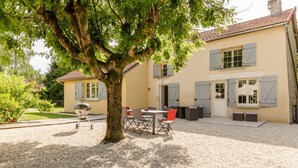 A house with a gravel patio, outdoor furniture, and a barbecue grill.