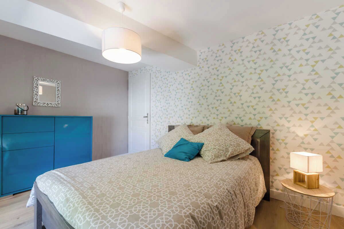 Une chambre à coucher avec un lit, une table de chevet, une commode et un miroir au mur.