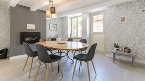 A dining area with a round table, six chairs, a fireplace, and a bench with a radio.