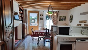 Una cocina compacta con comedor, microondas, estufa y una ventana con cortinas.
