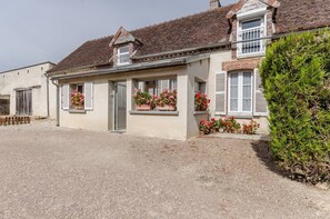 A two-story house with a gravel driveway, a front door, and flower boxes with red flowers. - Le Gîte de L'orvin - Bourdenay (BOURDENAY)