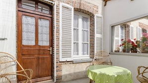 Zona d'estar a l'exterior acollidora, amb cadires de vimet i una taula coberta amb un mantell verd.