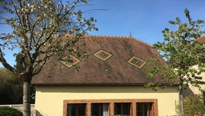 A house with a tiled roof, a yellow facade, and a garden with colorful flowers.