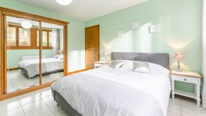 A bedroom with a large bed, two bedside tables with lamps, a wardrobe, and a mirror.