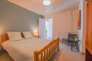 A bedroom with a bed, bedside table, lamp, and a view of the outside.