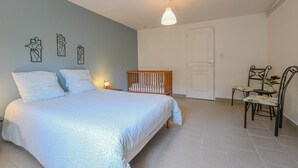 Ein Schlafzimmer mit einem Bett, einem Kinderbett, einem Stuhl und einer Tür.