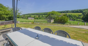 A table with chairs in an outdoor setting, overlooking a rural landscape with fields and a small building. - Le Gite de la CEA - SAINT MARDS EN OTHE (SAINT MARDS EN OTHE)