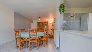 Ein Essbereich mit Holzsesseln, einem Tisch, einem Schrank und einer hängenden Pflanze.