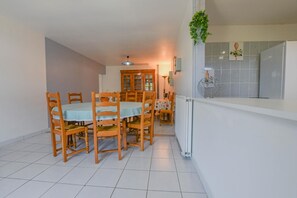 A dining area with wooden chairs and a table, a cabinet, and a hanging plant. - Le Gite de la CEA - SAINT MARDS EN OTHE (SAINT MARDS EN OTHE)
